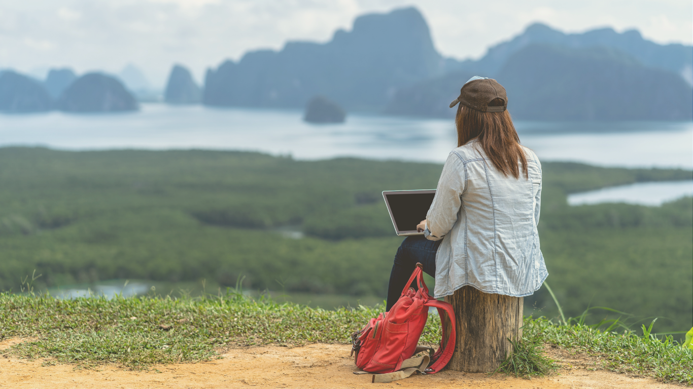 A digital nomad woman working on her laptop near a camper van, blending remote work with van life travel.